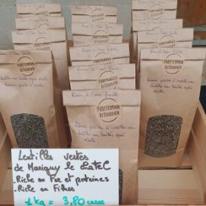Paquets de lentilles vertes artisanales dans une boîte en bois avec étiquette de prix et bénéfices.